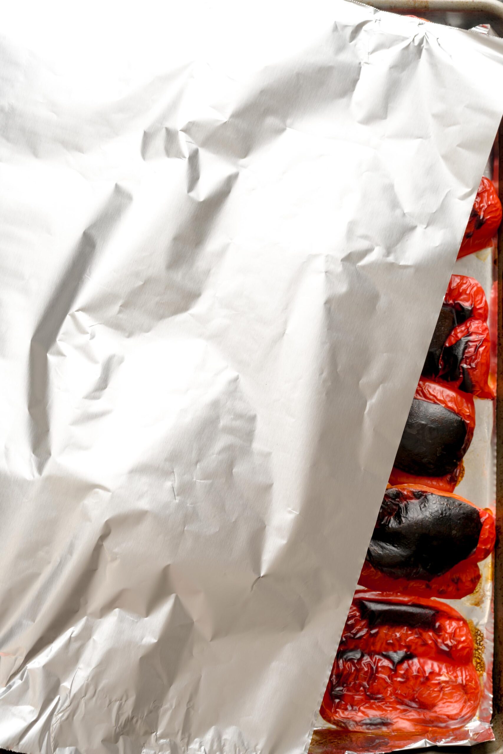 Aluminum foil tented over oven-roasted red peppers.